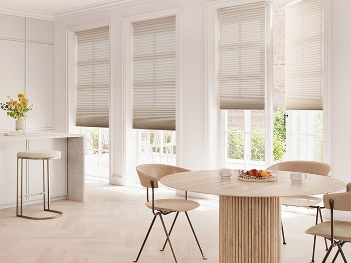 white room with tall French style windows, white marble countertops and light white washed round wood table with beige chairs.  